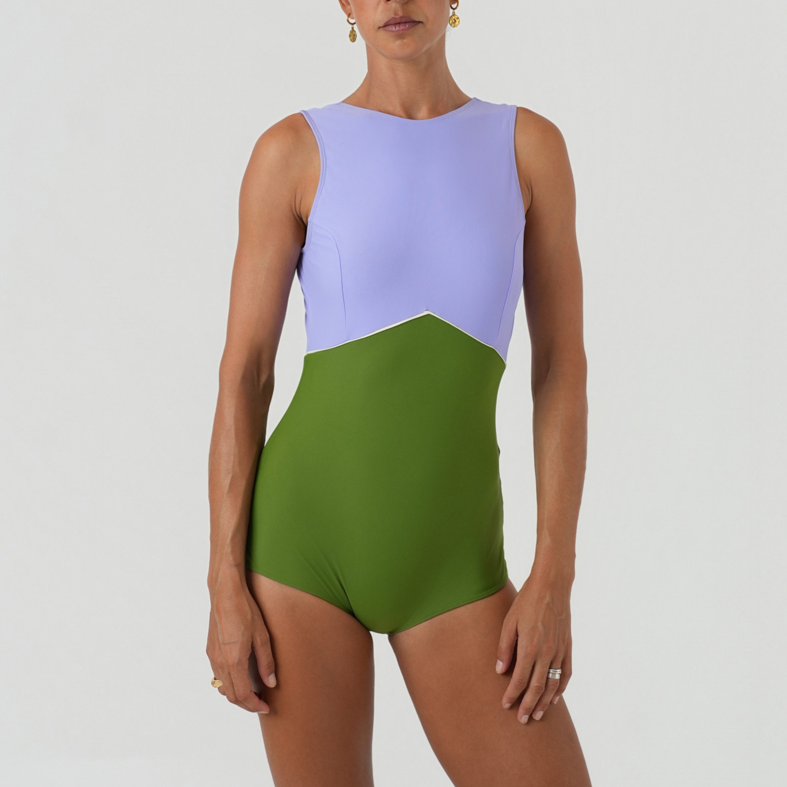 Woman wearing a two-tone swimsuit with purple top and green bottom 