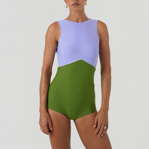 Woman wearing a two-tone swimsuit with purple top and green bottom 