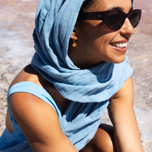 Woman wearing a blue headscarf and sunglasses with a blurred background