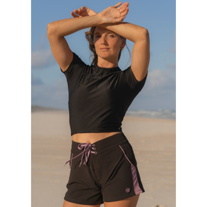 woman in black rashie and surf boardshorts