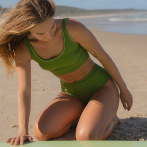 Woman in green bikini sitting on a beach