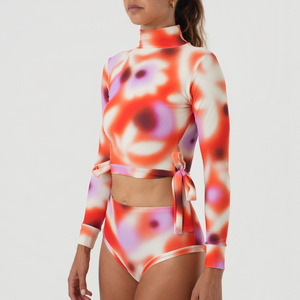 Woman wearing a colorful floral crop top and high-waist bikini bottoms