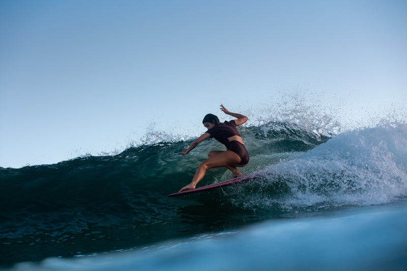 longboard surfer girl on a wave wearing a brown bikini