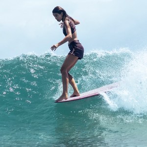 surfer wearing women boardshorts on the nose of a longboard